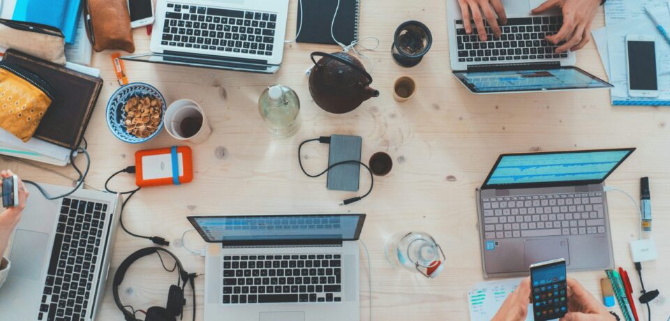 people sitting down near table with assorted laptop computers