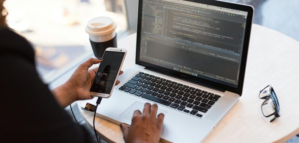 person holding smartphone while using laptop