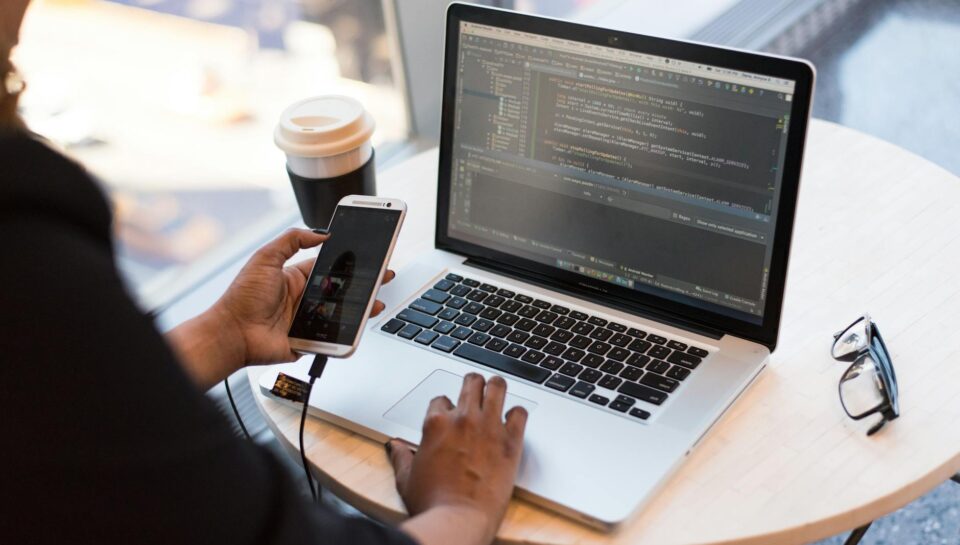 person holding smartphone while using laptop
